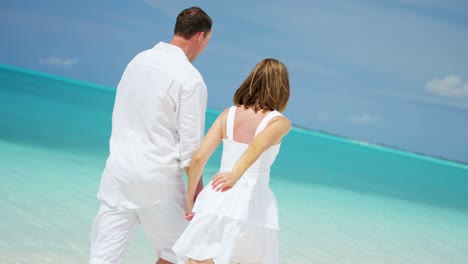 caucasian couple walking together on tropical vacation beach