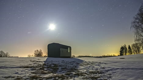 timelapse of a snowy landscape with a wooden cabin over which the milky way in the starry sky at dusk