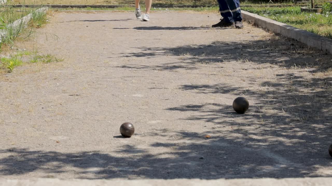 Menina joga bocha com homem em um campo.