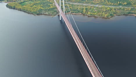 Aerial-View-Of-High-Coast-Bridge-Over-Ångermanälven-River-With-Autumn-Forest-Near-Veda,-Sweden