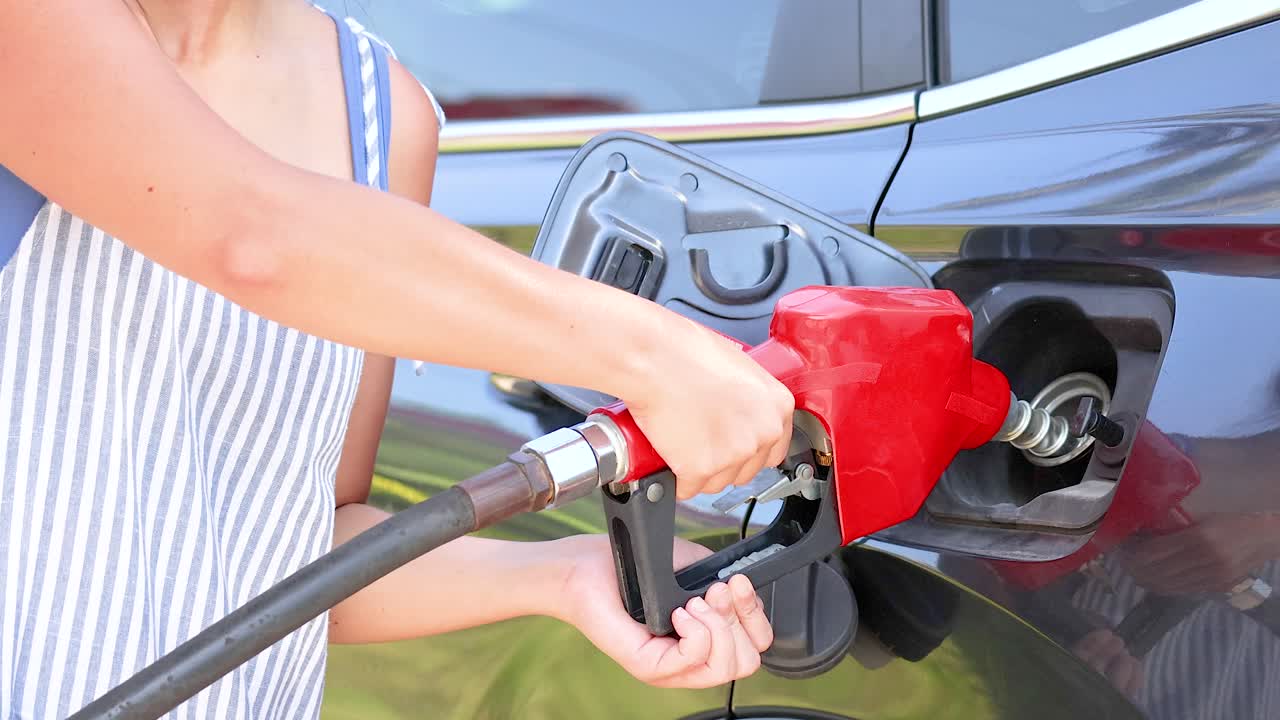 A person refuels a car at a coin-operated dispenser in bright daylight at Khao Rang Viewpoint, Phuket