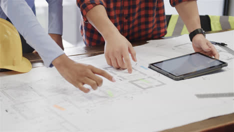 Midsection-of-diverse-male-and-female-architects-with-tablet-discussing-blueprints,-slow-motion