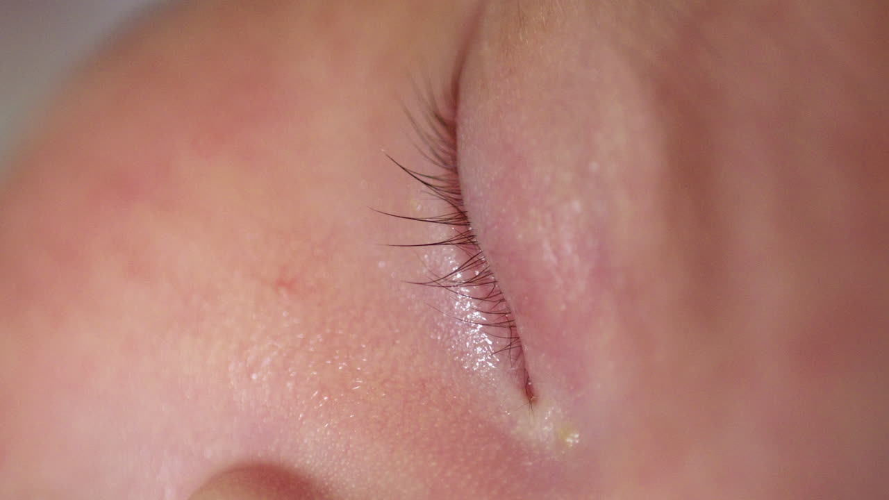 아시아 신생아의 은색 피부를 보여주는 잠자는 아기의 닫힌 오른쪽 눈의 클로즈업