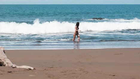 woman wading in ocean waves on sandy beach