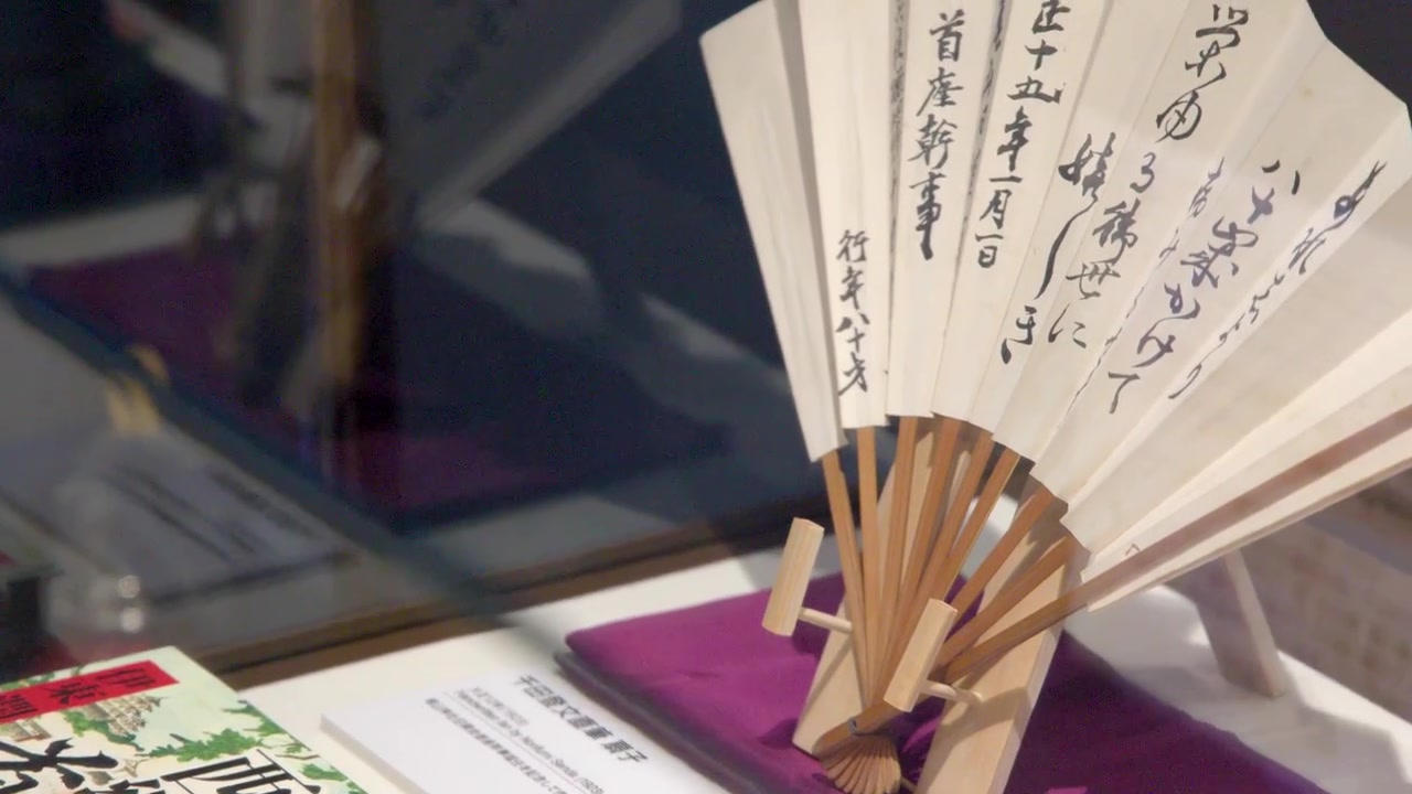 Bir müzede geleneksel bir Japon yelpazesi ve kitaplar üzerinde yakın çekim bir kamera kaydırma yapıyor.