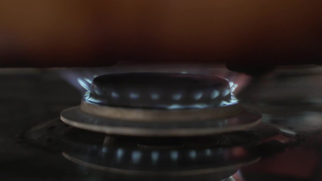 Primo piano della fiamma di un fornello a gas, mentre si cucina a casa.