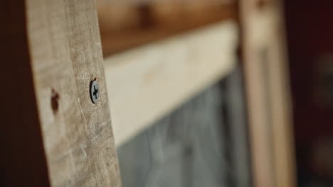 close up of drill removing screws from a wooden project