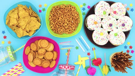 decoraciones de fiesta con comida y pasteles con crema blanca moviéndose en la mesa con velas y confeti de cumpleaños - detenga el movimiento