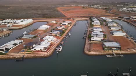 drone aerial panning over houses on a river harbour in exmouth surrounded by the outback