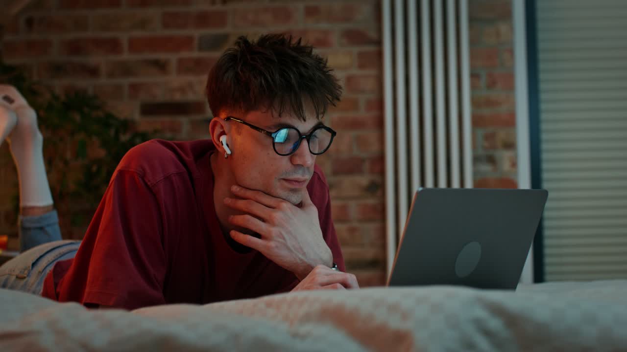 joven trabajando en una computadora portátil en el dormitorio