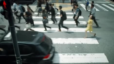 crowds of people hustle across a busy crosswalk in a vibrant urban area. the atmosphere reflects the energy of city life during midday, showcasing diverse individuals on the move.