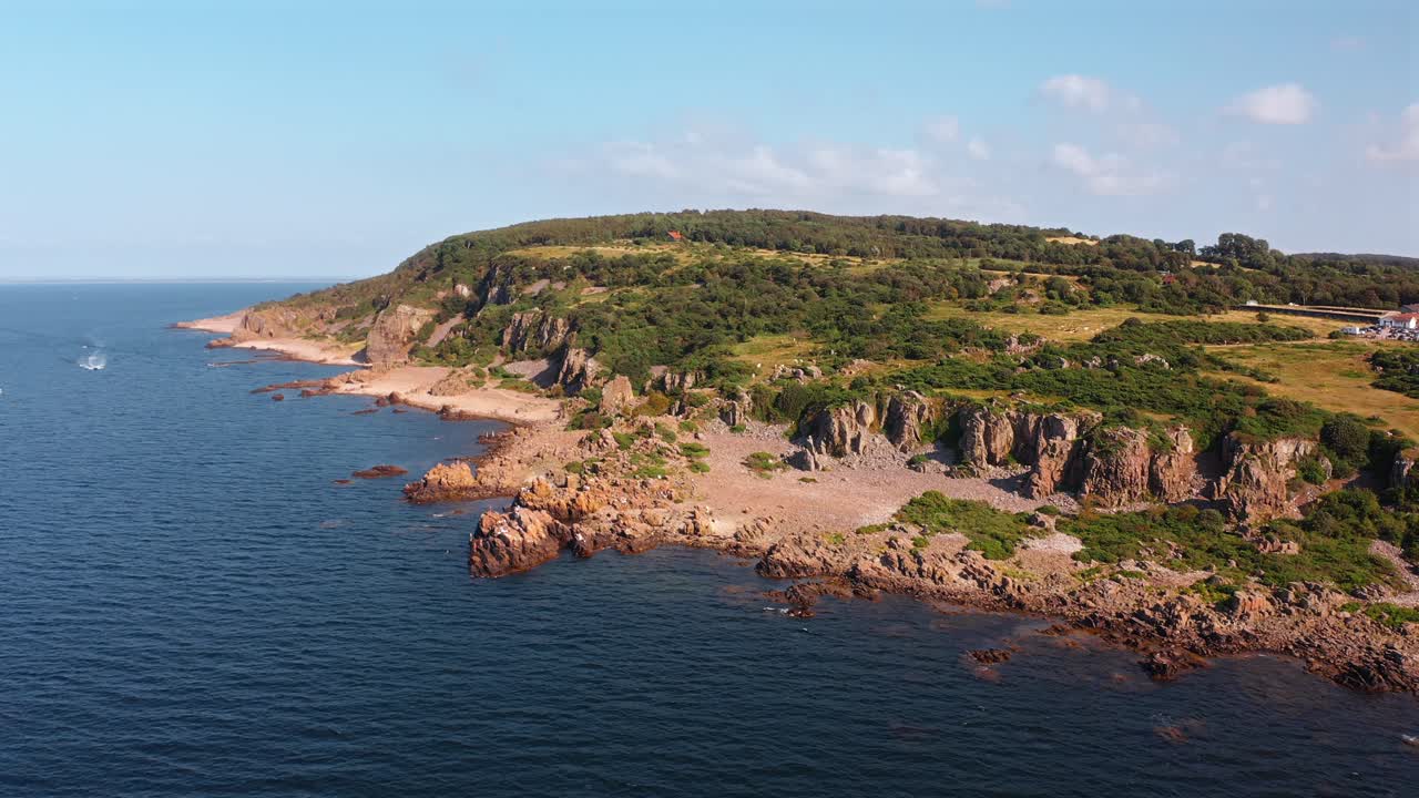 Beautiful aerial shot of a rocky coastline in Norway with lush greenery and ocean waves
