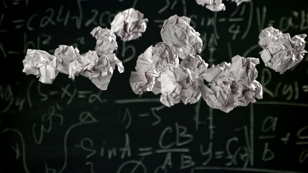 Rallentatore di carta accartocciata che cade contro equazioni matematiche