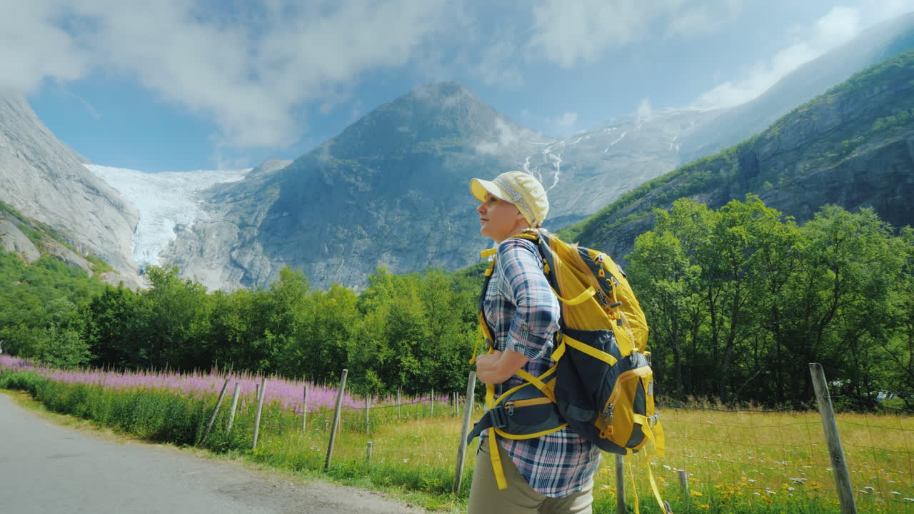 Kobieta idzie ścieżką do lodowca Briksdal w Norwegii, widok od tyłu. Podróżowanie po Skandynawii.