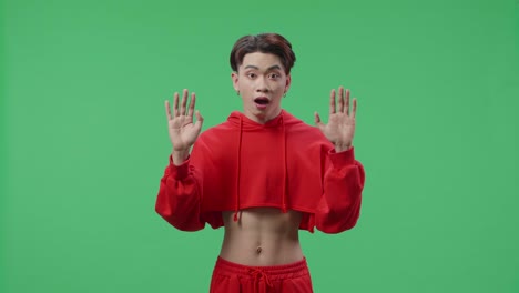 portrait of a young asian transgender male opening her eyes with palms and becoming surprised in the green screen studio