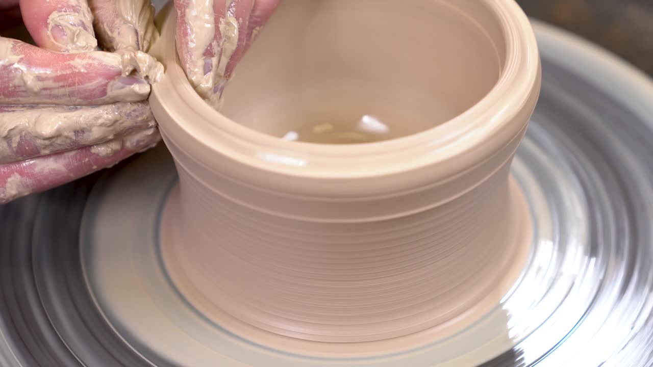 은 손이 회전하는 도자기의 바에 점토를 만드는 클로즈업입니다.