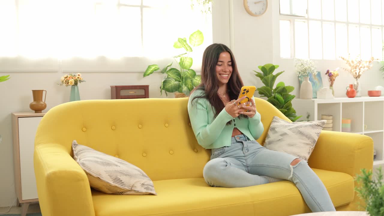 A woman using a phone on a yellow couch