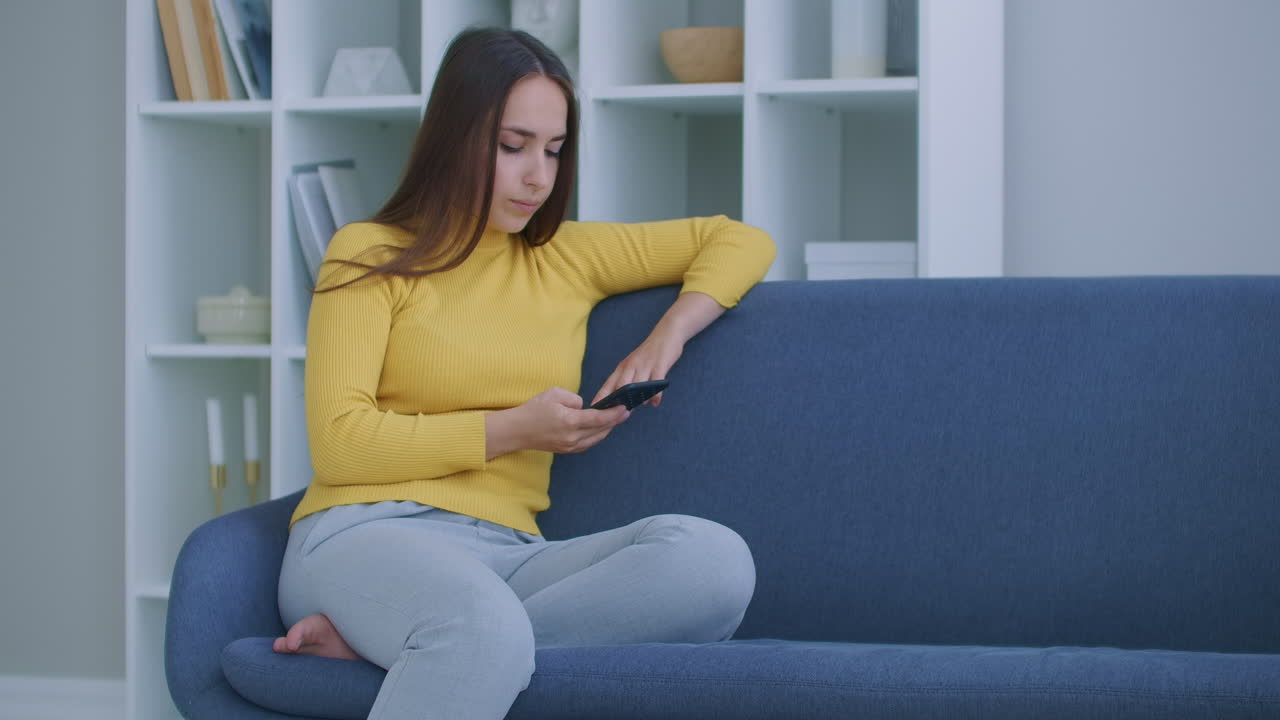 스마트폰을 사용하는 여성. 현대 스마트폰 터치 스크린을 사용하는 예쁜 소녀가 집에서 웃고 있습니다.