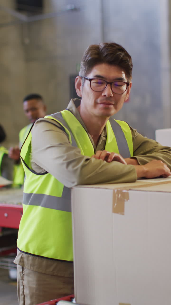 video vertical del retrato de un trabajador masculino asiático con una caja en el almacén