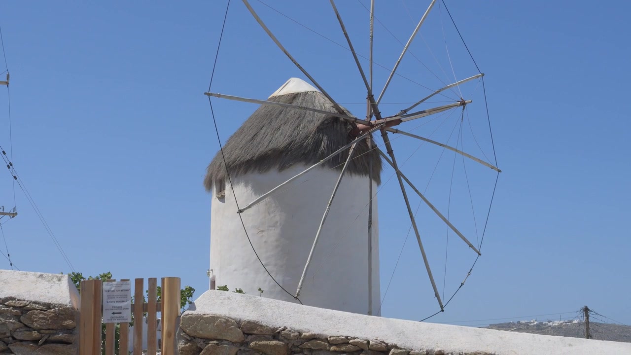 Majestætiske Bonis Vindmølle, et ikonisk vartegn på Mykonos, badet i sollys under en klar blå græsk himmel