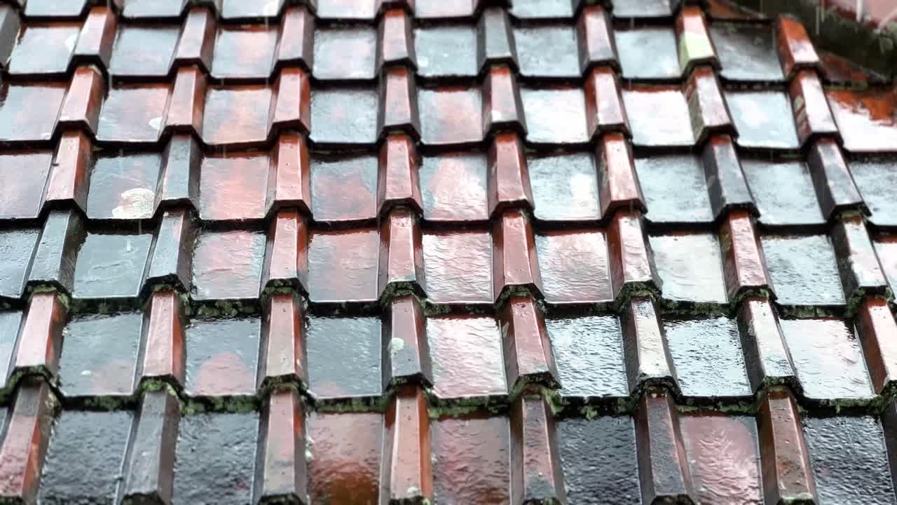 el agua de lluvia cae y fluye sobre las baldosas del techo de la casa