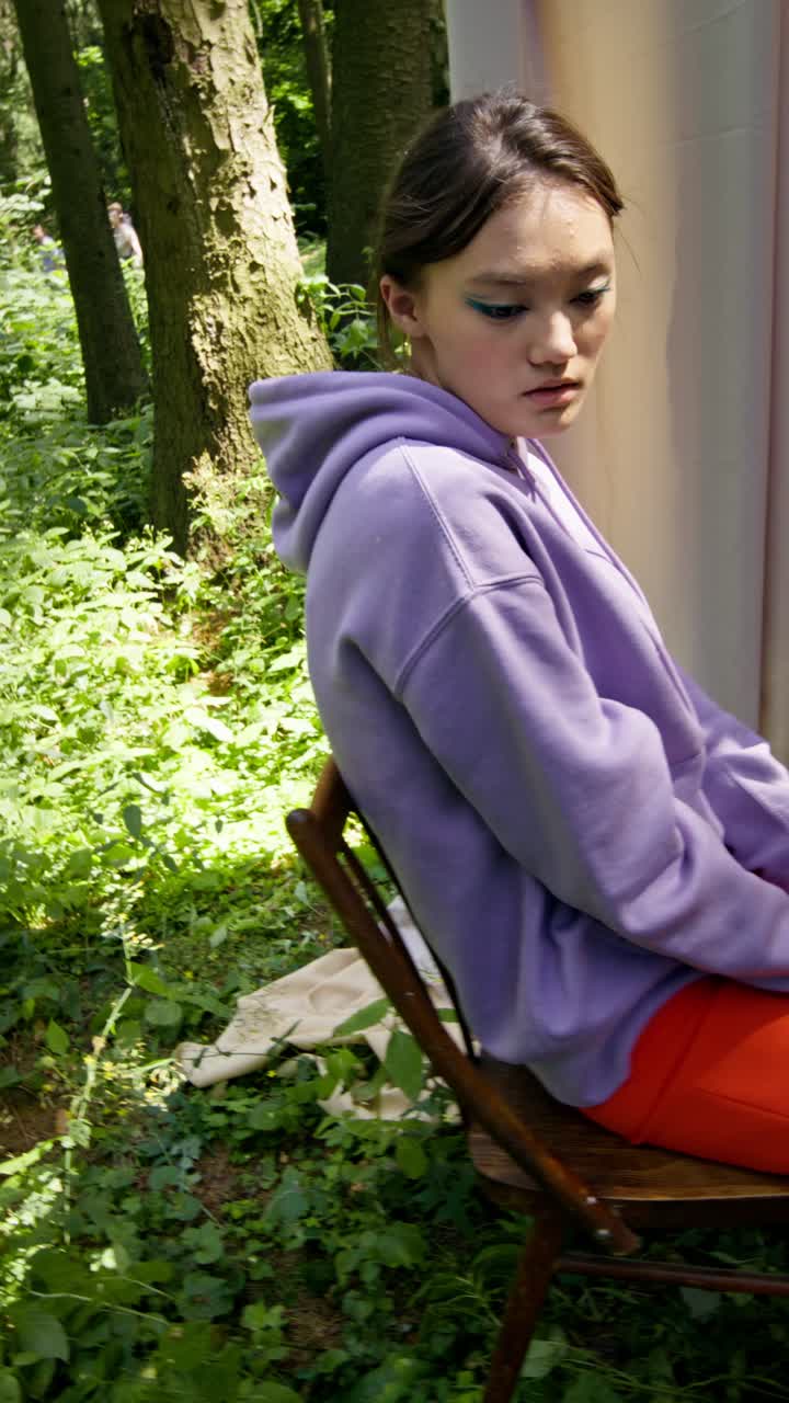 A woman in a purple hoodie sitting in a forest
