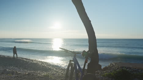 man walks along stony seaside, gathering stones and tossing them into the sea during an early morning stroll