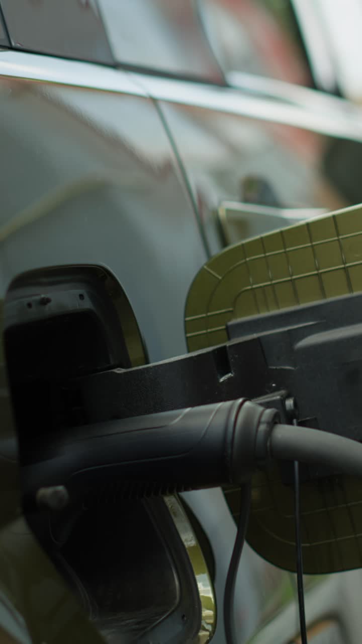Vertical video Close up of driver opening EV car charging port flap, attaching electric cable