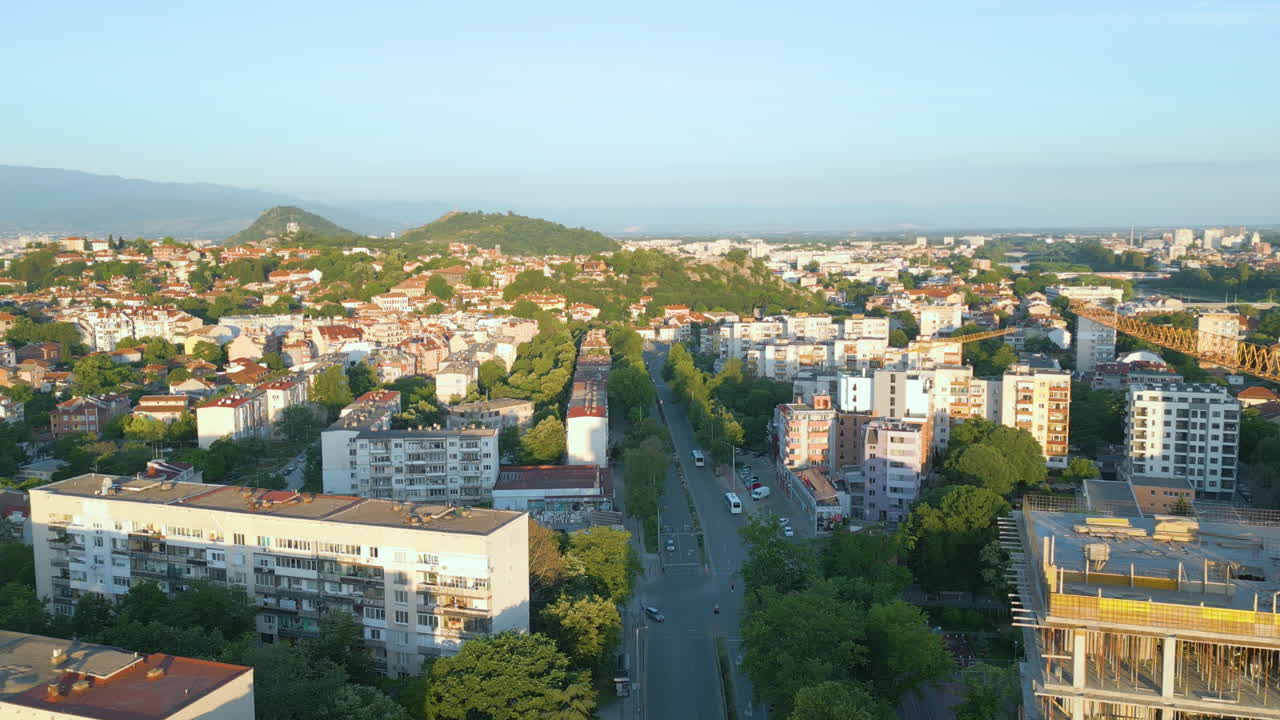 Aerial view of Plovdiv at sunrise in spring. The Bunardzhik Hill and Youth Hill dominate the background, surrounded by green trees and residential buildings