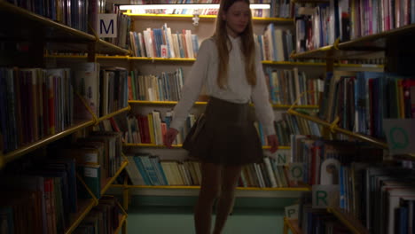 schoolgirl choosing a book for reading in the school library, handheld shot