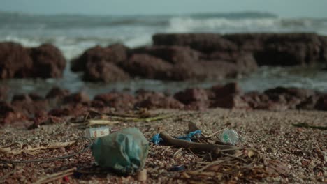 Müll-Und-Schutt-Verstreut-Auf-Einem-Felsigen-Strand-Mit-Wellen-Im-Hintergrund