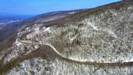 Aerial-drone-video-footage-of-a-snowy,-blue-sky-mountain-valley-road-highway-through-the-mountains-in-the-Appalachians-on-the-Shawangunk-ridge,-in-new-York-state