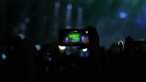 concierto de filmación, silueta de fanáticos de la música fotografiando con un concierto de teléfonos inteligentes en una escena brillante