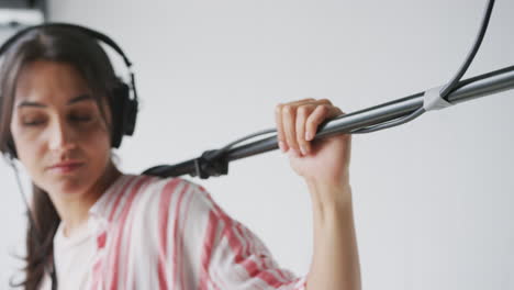 female sound recordist holding microphone on video film production in white studio