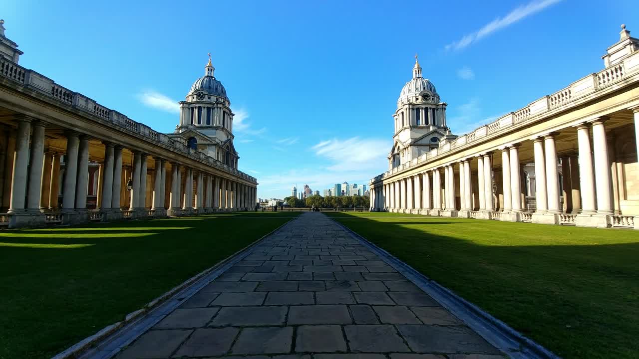 Cinematic view of the Old Royal Naval College in Greenwich, London, showcasing its grand baroque architecture, domed towers, and symmetrical colonnades under a clear blue sky, symbolizing heritage