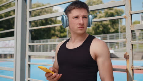 athletic caucasian man in sportswear enjoying listening to music in earphones from smartphone app