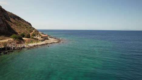 un dron vuela hacia una pequeña iglesia antigua junto al mar junto a un cementerio