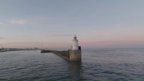 drone clip at golden hour showing picturesque lighthouse and harbout