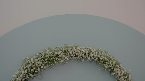 delicate wreath of baby's breath flowers arranged in a semi-circle against a light blue backdrop