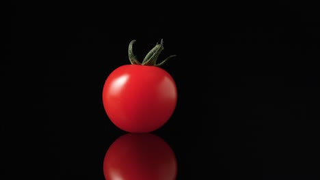 single red cherry tomato on black background