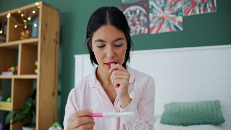 worried woman looking at pregnancy test in bedroom
