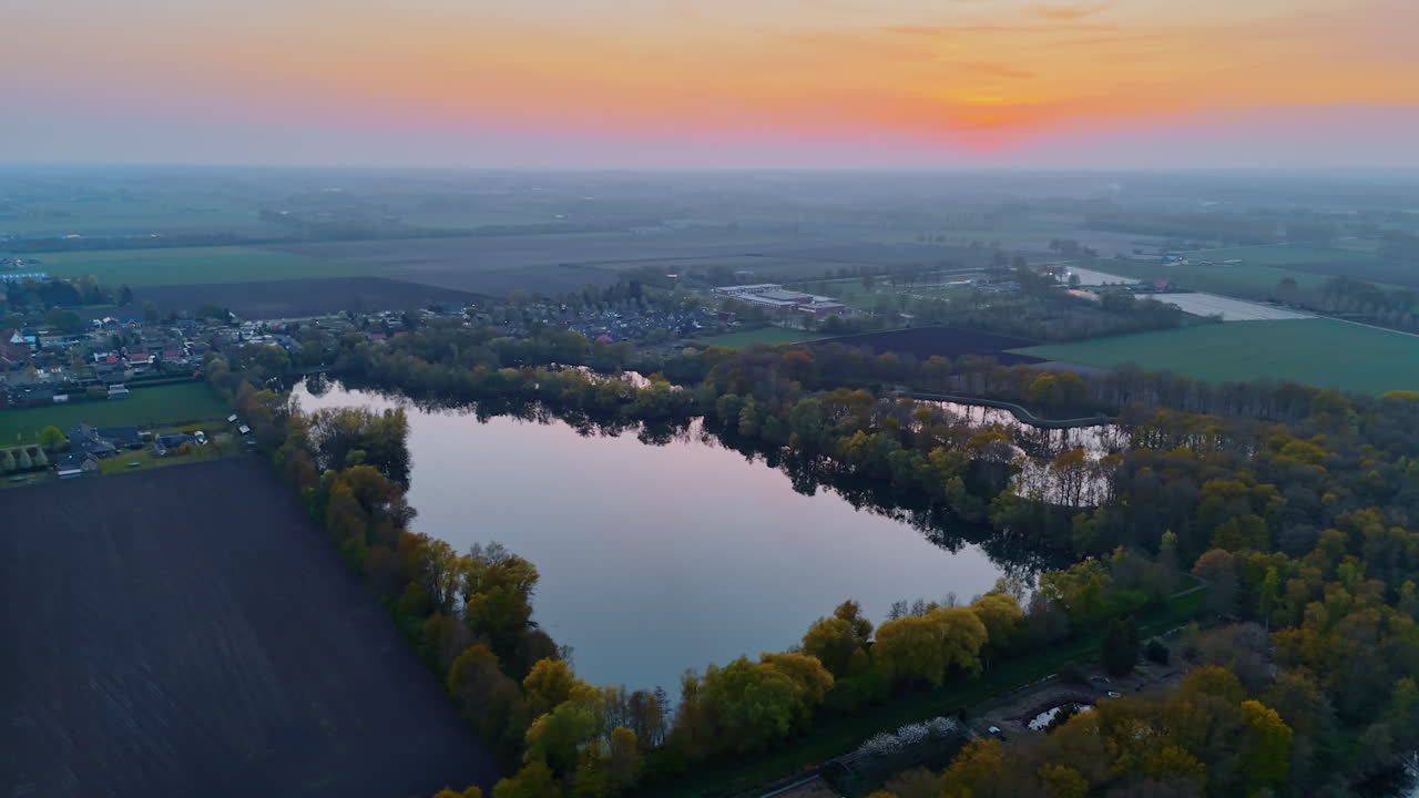 Tranquil Dutch dusk landscape. Vibrant sunset casts orange hues over serene lakes and lush greenery in the Netherlands countryside