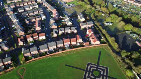 aerial view above new build modern housing estate tilt down to target pattern in field