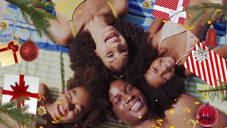 animation of christmas presents and decorations over happy diverse parents and children lying in sun