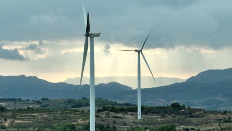 Aerogeneradores-Inoperativos-Y-Paisaje-Montañoso-De-Coll-De-Moro-En-Segundo-Plano-Con-Cielo-Tormentoso-Nublado,-Cataluña-En-España