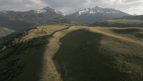 aerial: rolling green meadows on summit plateau in rocky mountains