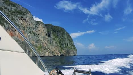 The-view-from-the-back-of-a-mid-size-boat-surrounded-by-the-blue-sea-and-a-green-island-to-the-left