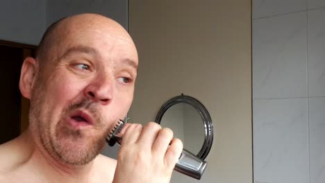 male shaves with an electric razor