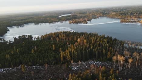 Drone slowly flying over forest towards a beautiful frozen lake in the Swedish Wilderness