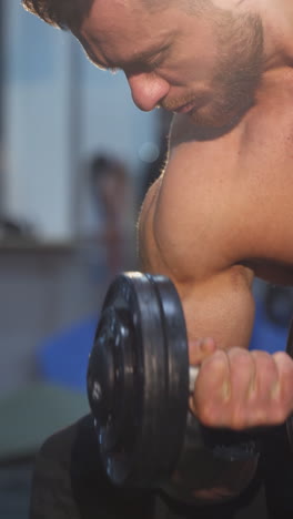 young muscular man training hard at the gym. bodybuilding man training his biceps. vertical video